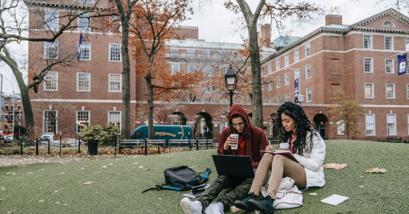 Two people studying in front of a university